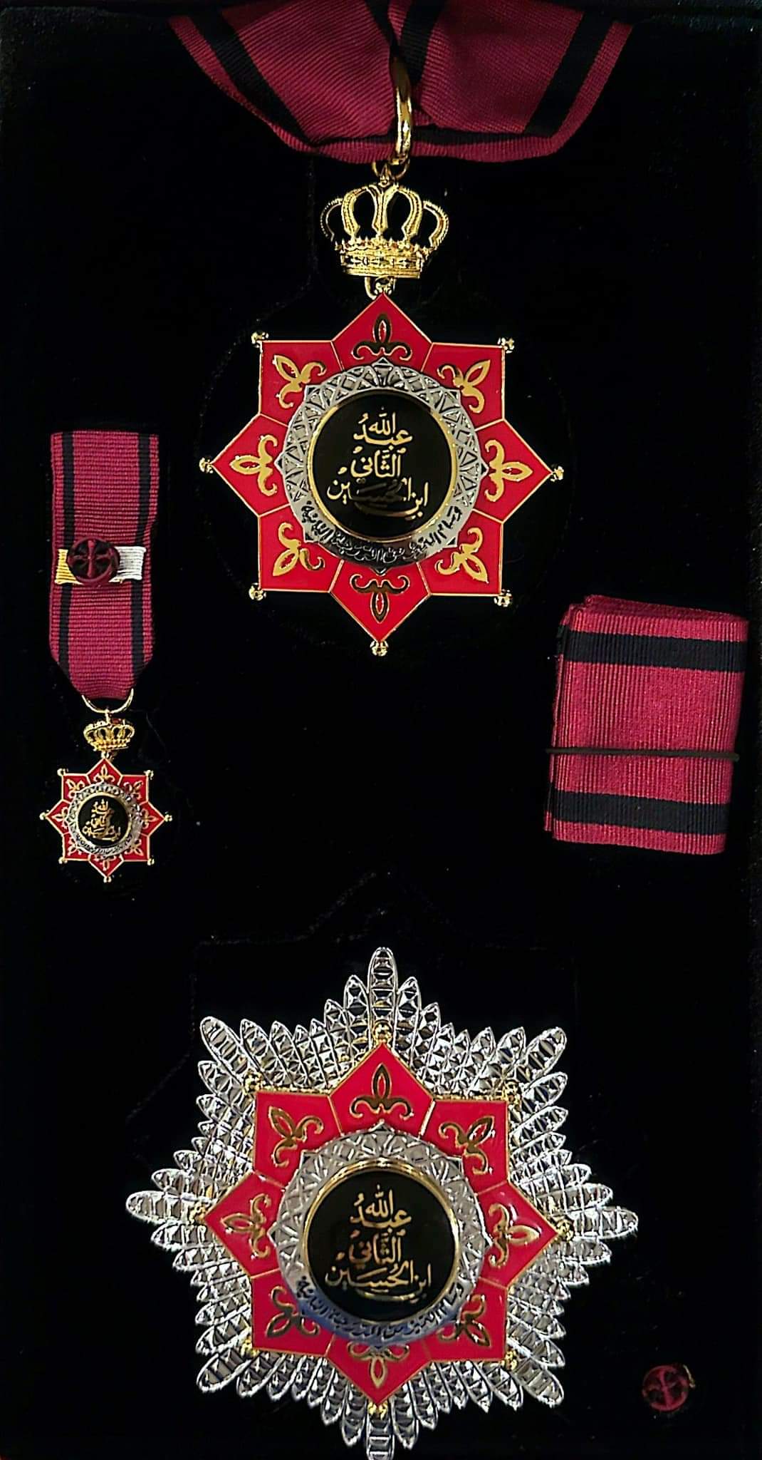A composite image of different close ups of the medal. The medal consists of a black circular centre with arabic writing in gold, surrounded by a red eight-pointed ornate star embosed with gold. The medal is attached to a red and black woven ribbon by a gold crown.