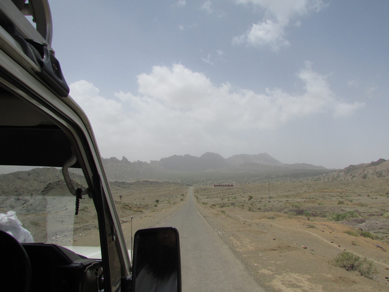 A desert view with mountains in the background and a road leading into the distance.